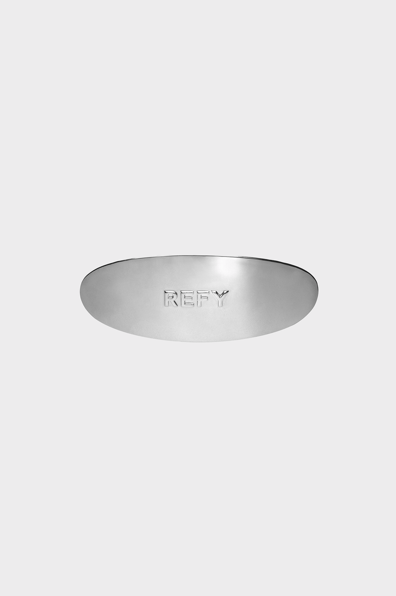 CLOSE UP OF REFY METAL OVAL HAIR CLIP WITH EMBOSSED REFY LOGO